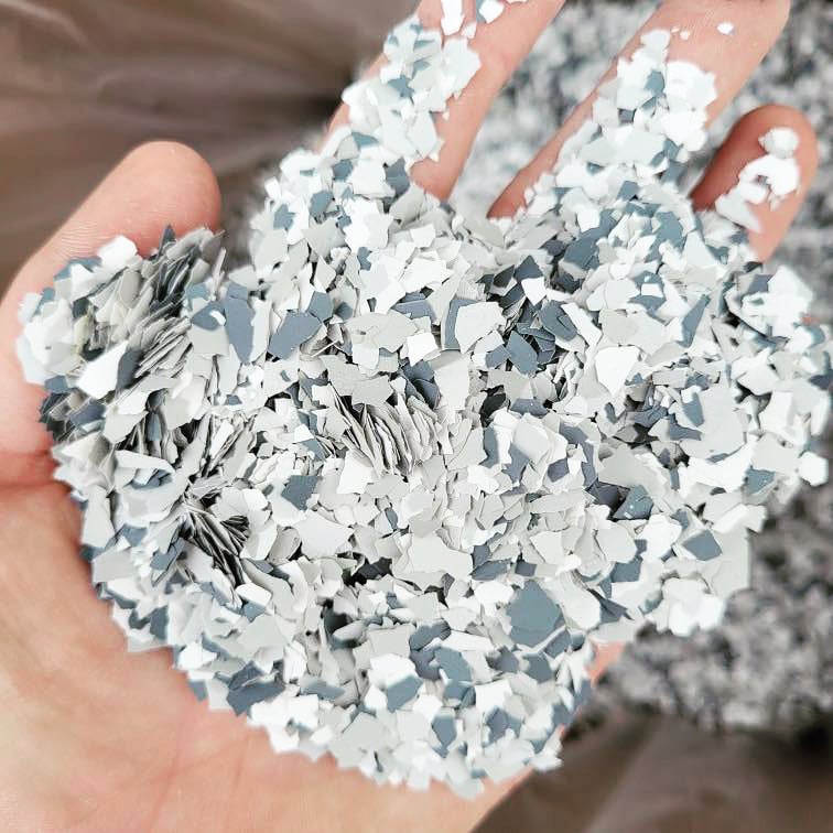 A person's open hand displaying a collection of small, irregular-shaped, metallic blue and silver confetti pieces, providing a textured and vibrant appearance.